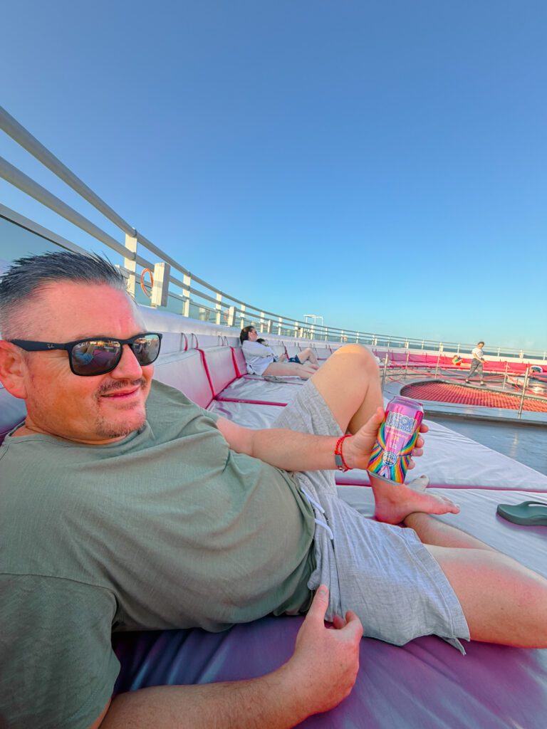 mike enjoying a beer on the deck of virgin voyages cruise